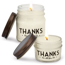 two white candles in glass jars with thanks message